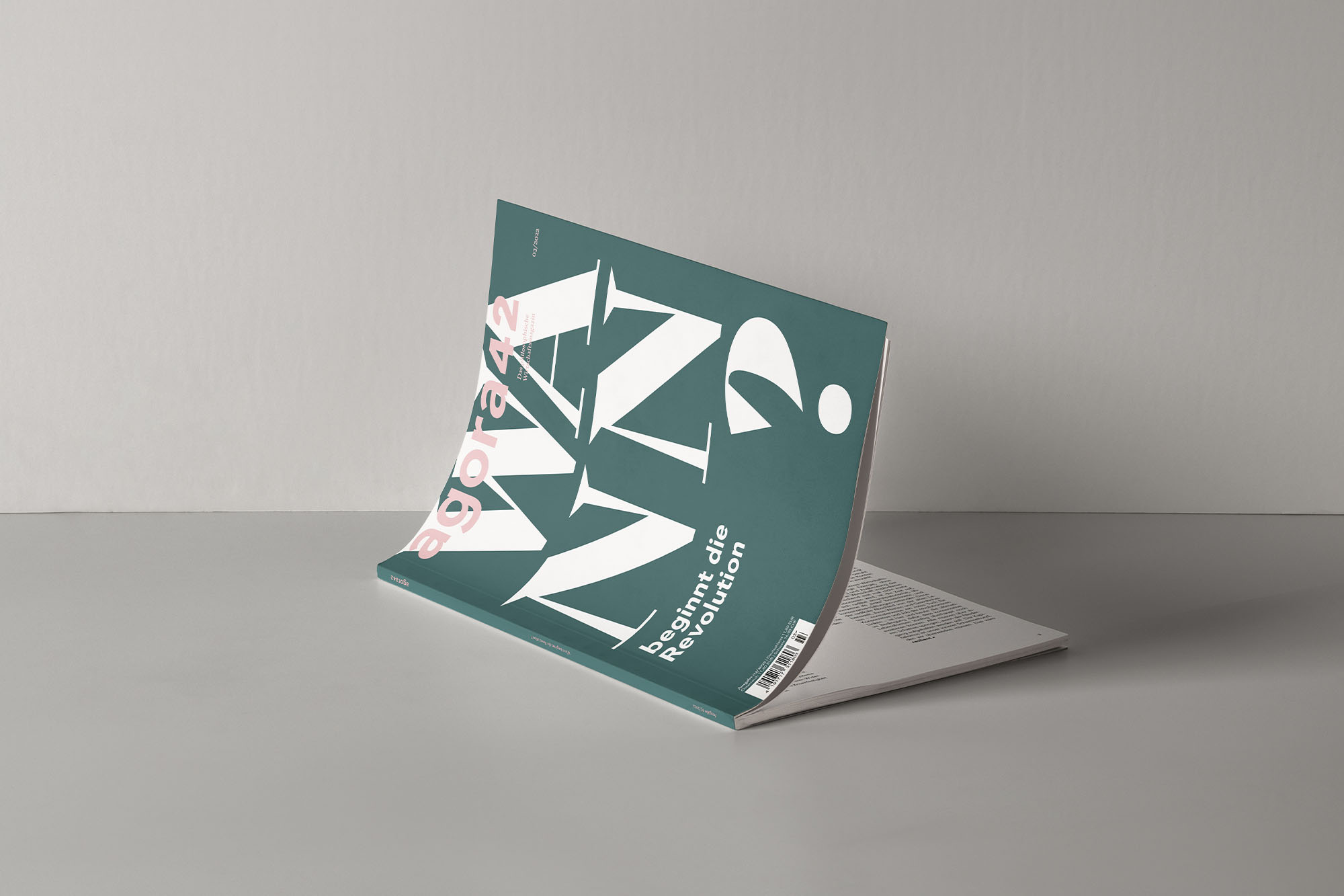 Ein aufgeklapptes agora42-Magazin der Ausgabe "Wann beginnt die Revolution?" liegt auf dem grauen Boden vor einer grauen Wand.